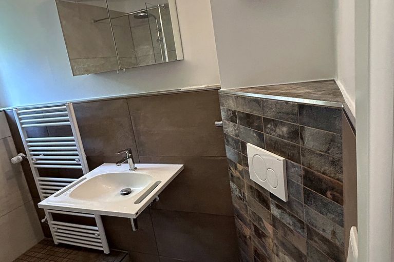 Neu gefliestes Bad mit Mosaik-Akzentwand und Vorwand-WC